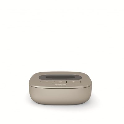 The Phonak TV-Link II Base is a beige electronic device featuring a display screen and three buttons—power, plus, and minus—shown against a plain white background.